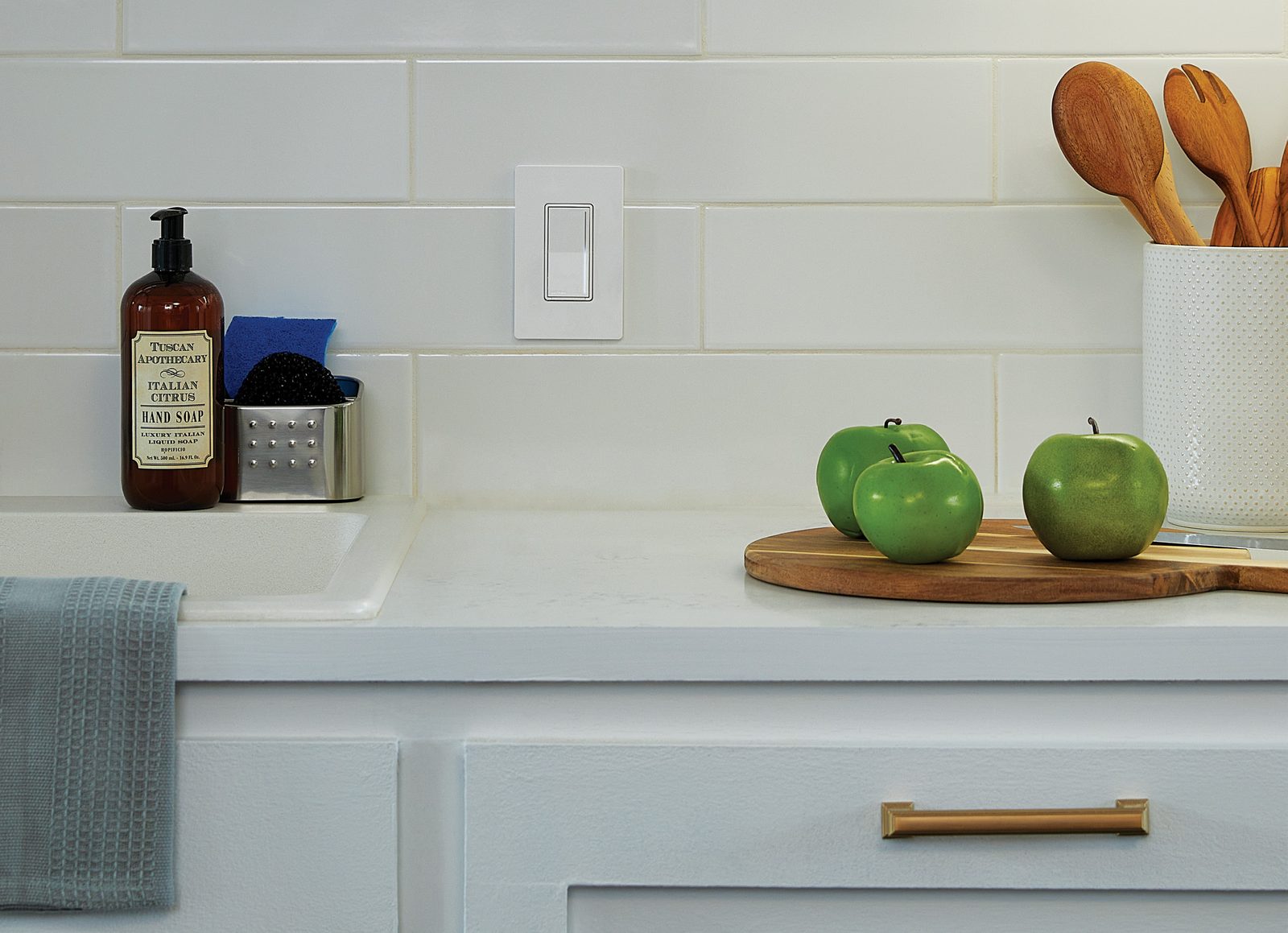 A slim Lutron Sunnata dimmer on a white kitchen backsplash